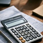 Financial calculator showing loan principal and interest breakdown with payment schedule on desk