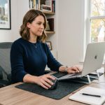 Person using a vertical ergonomic mouse at a desk to ease wrist pain.