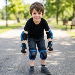 Child wearing knee and elbow pads safely outdoors.