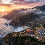 Aerial view of the Big Sur coastline with misty cliffs and the Pacific Ocean at sunset during festival season