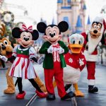 Mickey and Minnie Mouse waving to guests during Mickey's Very Merry Christmas Party at Magic Kingdom with Cinderella Castle lit up in holiday lights in the background