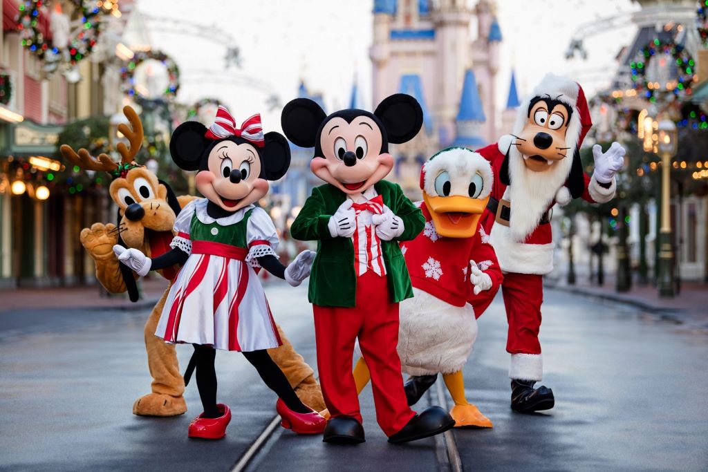 Mickey and Minnie Mouse waving to guests during Mickey's Very Merry Christmas Party at Magic Kingdom with Cinderella Castle lit up in holiday lights in the background
